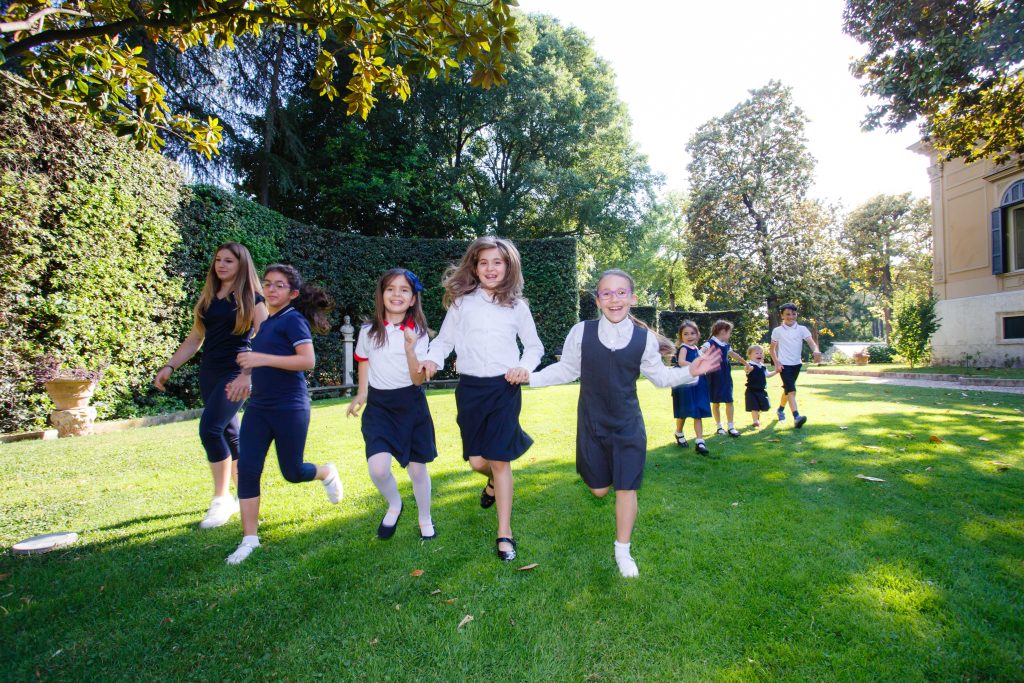 Smiling school children running outside in their back to school uniform