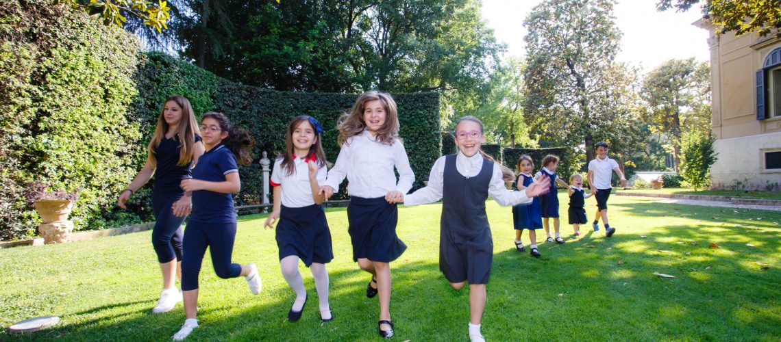 Smiling school children running outside in their back to school uniform